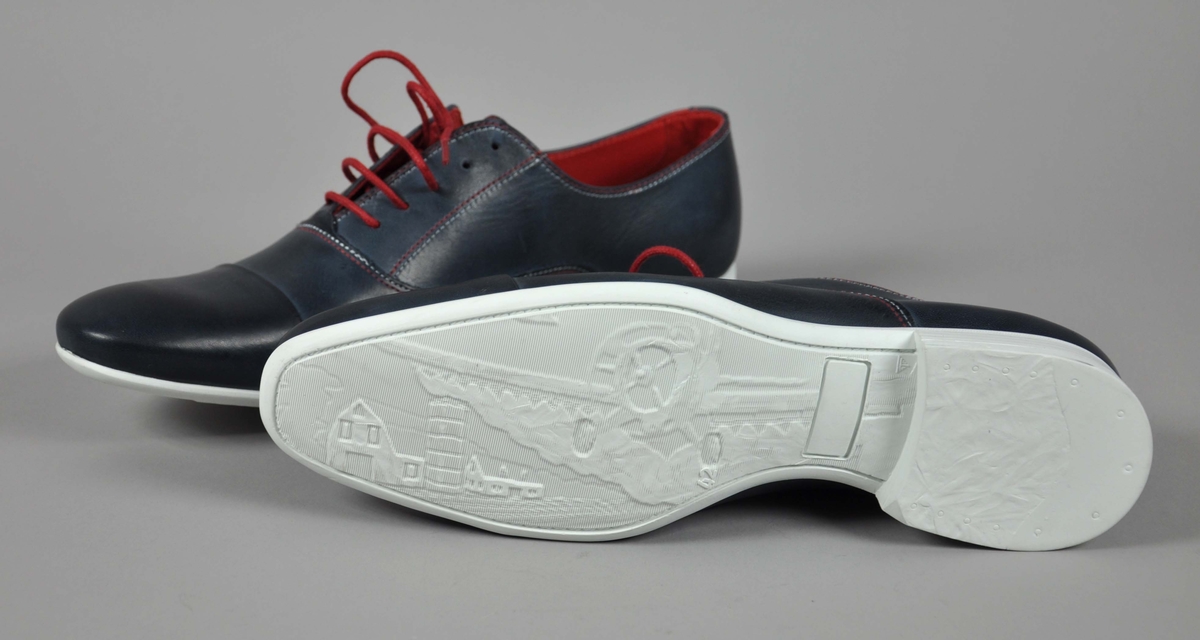 Et par blå skinn herresko i str.42,røde skolisser,røde og hvite sømmer .
Traktor-logoen påtrykt i hvitt på begge skoene.