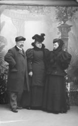 Portrett. Tre stående, godt voksne personer. S. Hansen med t