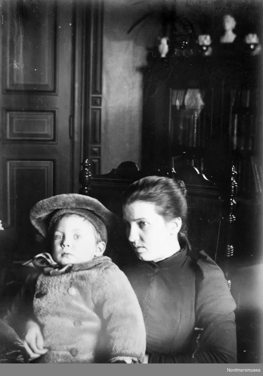 kvinne, barn med lue, stue ca 1900. Samlingen har tillhørt Gert Faye-Gunnerud hvis mor var fra Walther-slekten i Kristiansund. Giver av samlingen er Tore Kristiansen. Fra Nordmøre museums fotosamlinger.
