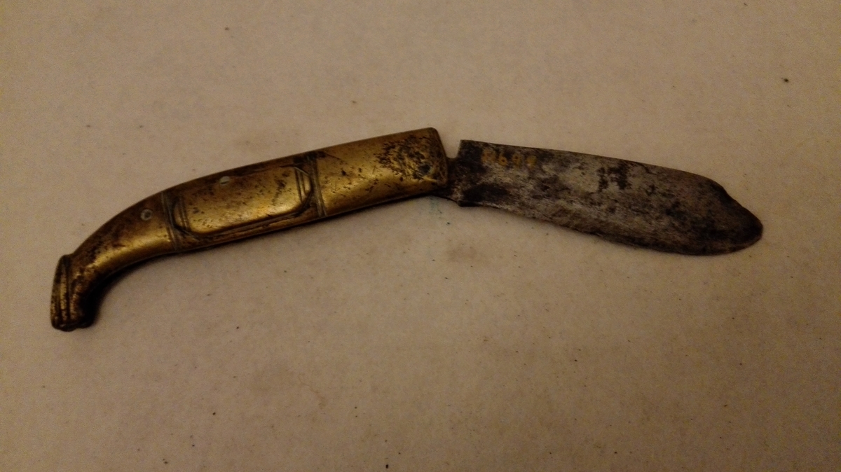 1 kniv.

Hjemmesmidd foldekniv med messing beslaaet skaft i form av en fot. Fra Lærdal.

Samtlige disse gjenstander (11643 - 53) Kjöpt ved Kjöbmand Th. Lindström, Lærdal.

