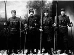 Portrett av fire unge menn i uniform og med skiutstyr