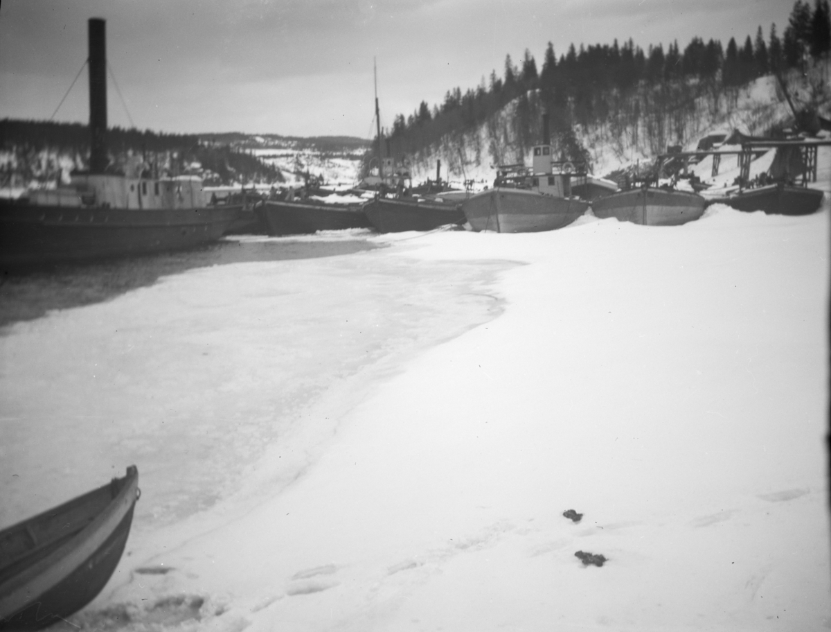 Båter i opplag i vika på Minnesund vinterstid, i forgrunnen D/S Thor, i bakgrunnen D/S Industri II og Industri samt lektere