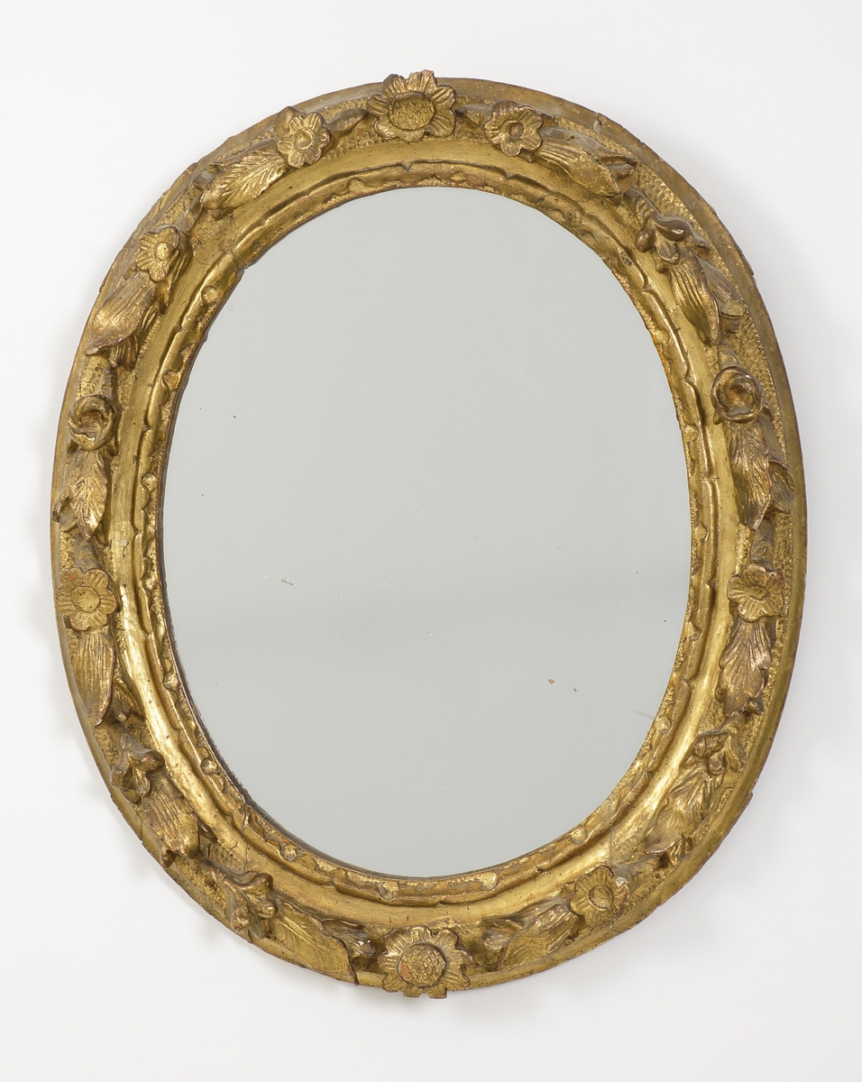 Spegel, rokoko. 
Oval modell. Förgylld träram med blomsterdekor och bladverk i hög relief. 
Saknar signering/stämplar.