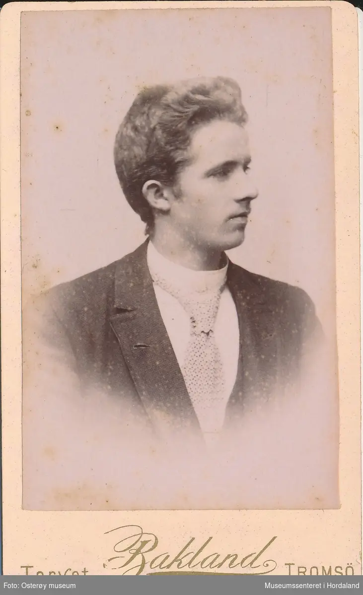 portrettfotografi av ung mann med mørk jakke, kvit skjorte og snipp/slips kombinasjon