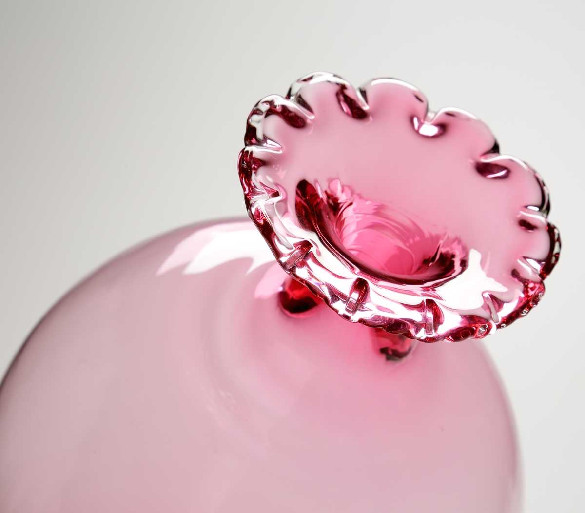 Vas eller pokal.
Stilen på glaset är gjord så att den ska se ålderdomlig ut.
Hög rosa vas/pokal som vidgar sig uppåt, och avslutas i en smal hals med utvikt mynning. Mynningen är veckad.
Benet är ofärgat och balusterformat.  
Foten rosa.