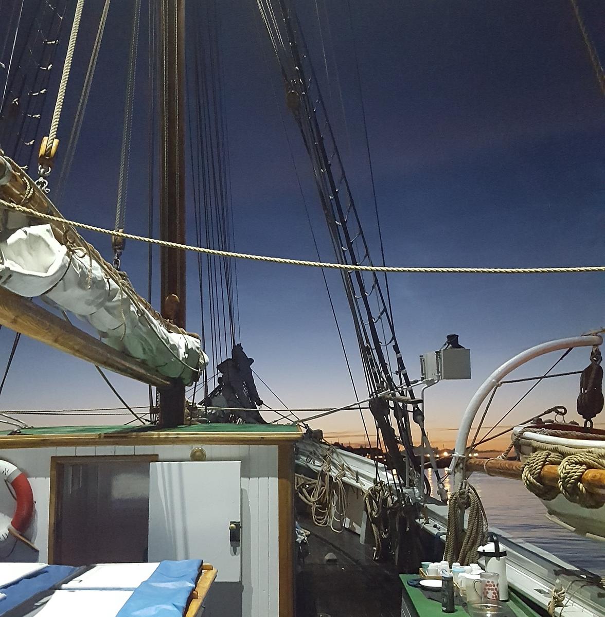 Detalj av skonnerten "Svanen", mast med rigg, detalj av livbåt, mørkeblå himmel.