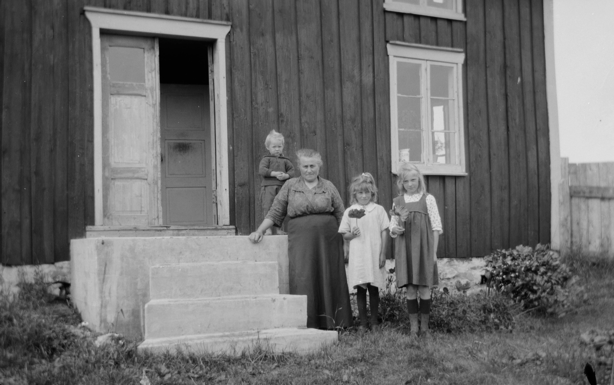 Kvinne, to jenter og en gutt står ved inngangsdør.