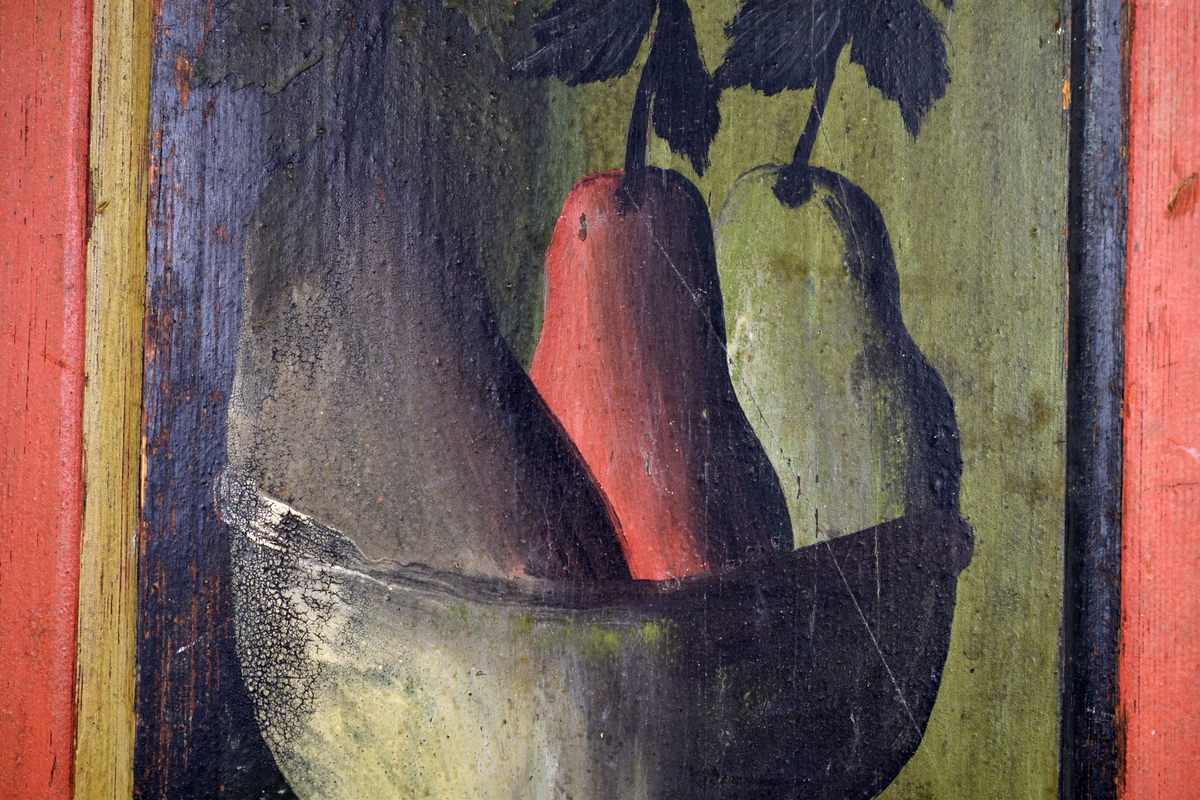 Rektangulärt dörrfält till skåp. Runt kanterna rött, på fältet en målad skål med tre päron.