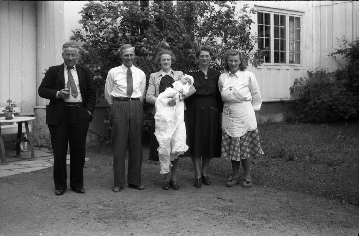 Fra en barnedåp. Dåpsbarnet er sannsynligvis Henning Johansen. Lengst til høyre står barnets mor, Mary Johansen (f.Ulsrud). Nummer to fra venstre er faren, Johan Johansen. De tre øvrige er ikke identifisert.