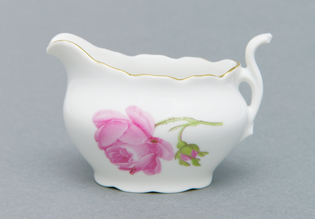 Oval fløtemugge av porselen med glasur og knekt hank. Med rosemotiv i rosa og grønn, samt bølgete gullkant.