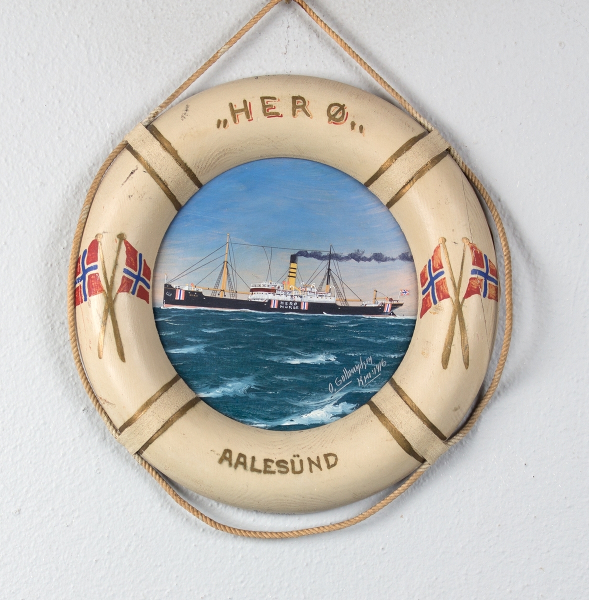 Skipsportrett av DS HERØ under fart i rom sjø. Rammen er utformet som en livbøye dekorert med norske flagg og skipets navn og hjemmehavn. Skipet har påmalt nøytralitetsmerker på skutesiden.