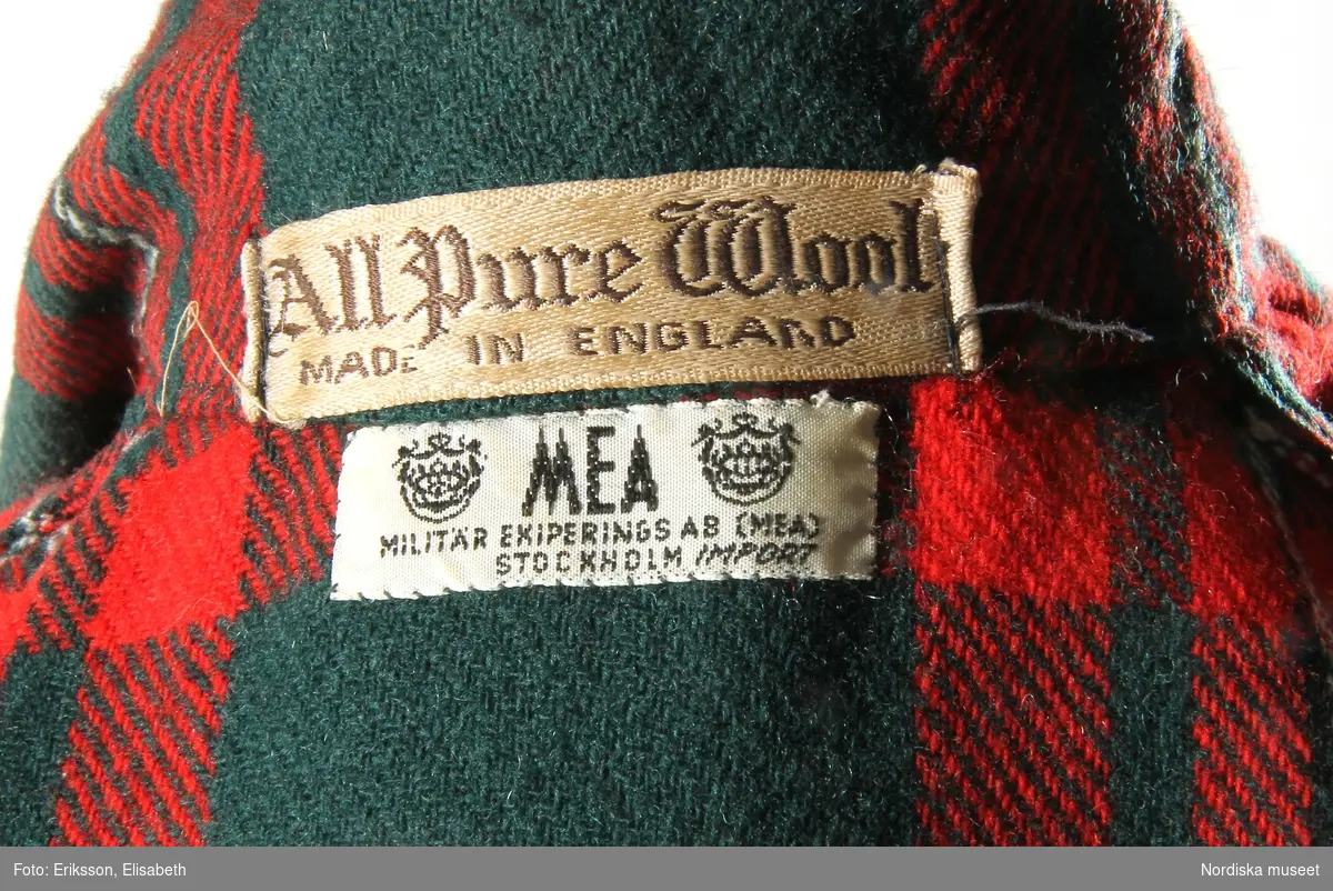Morgonrock, 1950-60-tal, engelskt fabrikat av kyprat skotskrutigt ylle.
Grön botten med rutor i rött, vitt och svart. 1 bakstycke, 2 framstycken. Krage med 2 rundade slag. Knytskärp i midjan. 1 påsydd ficka på var sida. Ärmarna med påsytt uppslag. 
Inköpt på MEA.