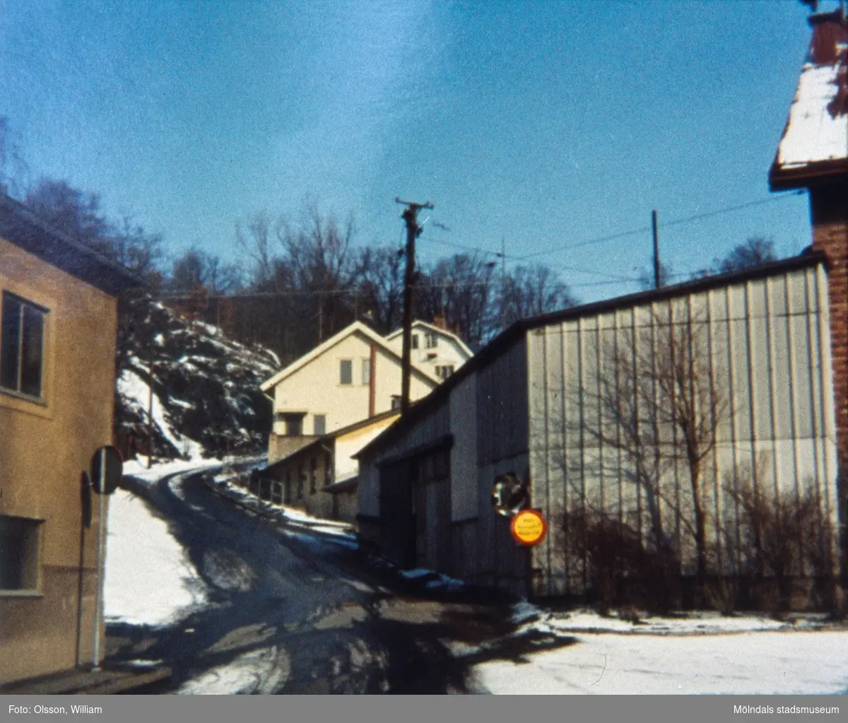 Samuel Norbergsgatan – Friareliden, okänt årtal. En backe svänger åt höger utefter Störtfjället. Fabriksbyggnad ses till vänster och garage samt villor till höger. Elledningar passerar över byggnaderna och det är snö och halka på marken.