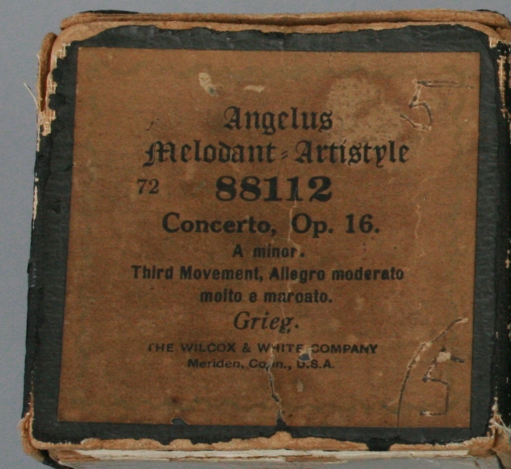Musikkrull med eske til selvspillende piano. 
Angelus Melodant, Artisyle system (flere patenter i ulike land godkjente mellom 12/5 1891 (US) og 10/9 1907 (US).