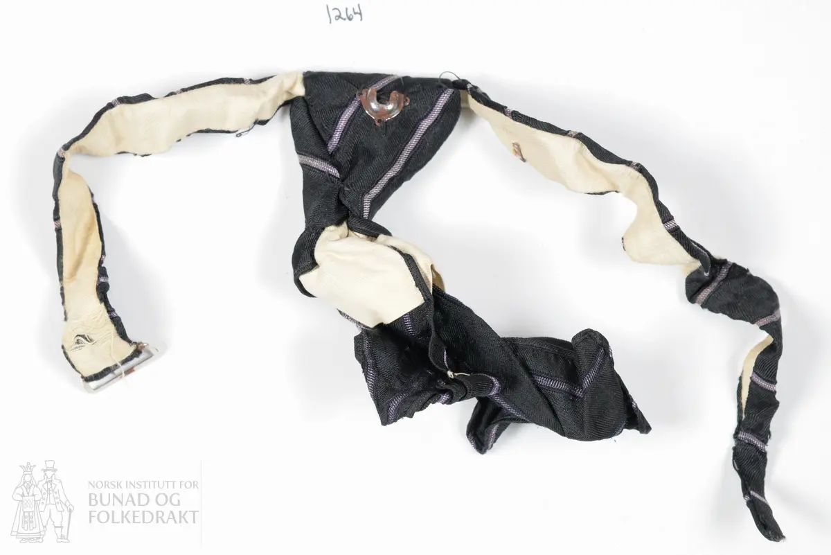 Slips i svart silke med metallhekte i enden. Silke, kypertvevd bunn, stripeeffekt i lilla og hvitt. Maskinsøm.