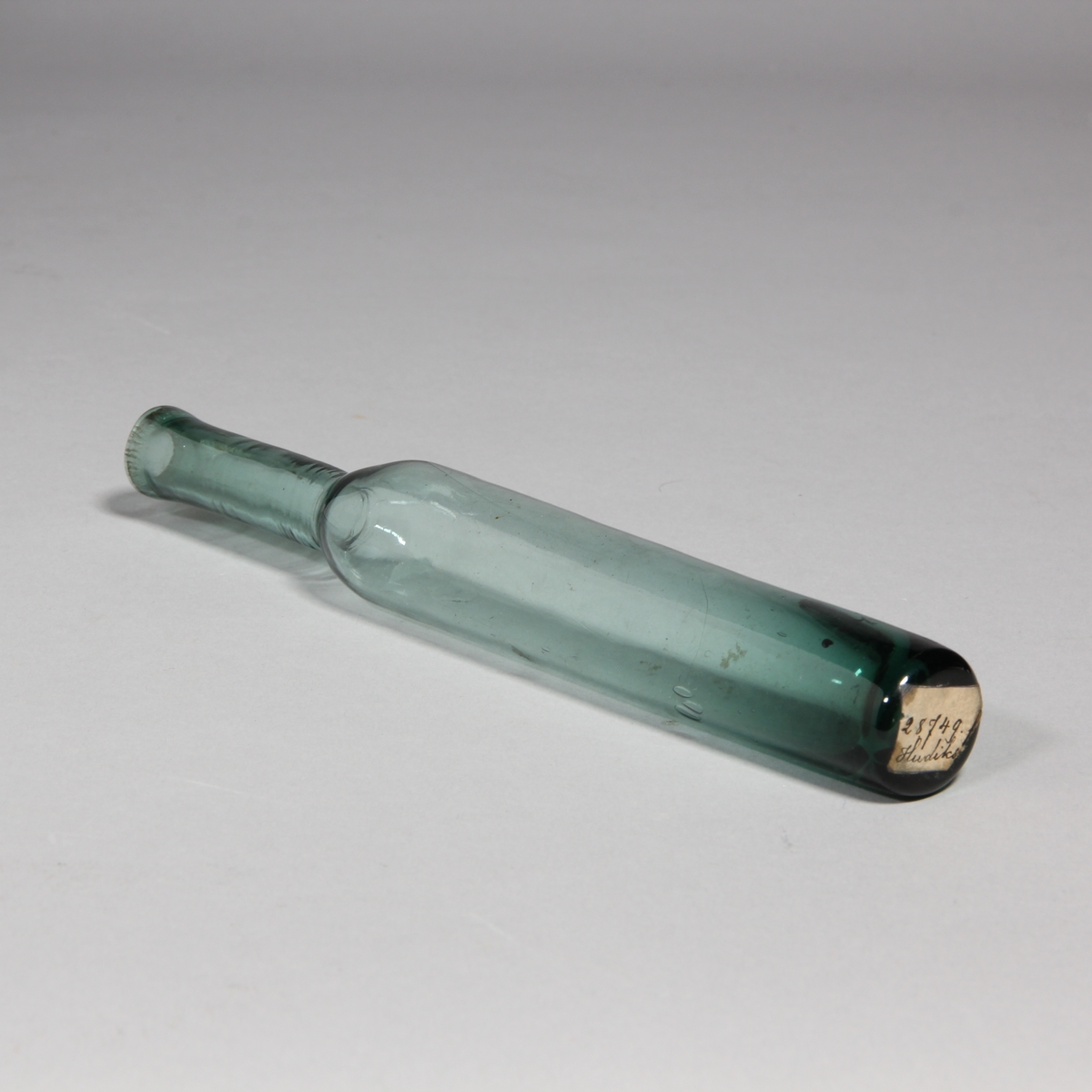 Luktvattenflaska av grönt glas, cylindrisk med hög hals.