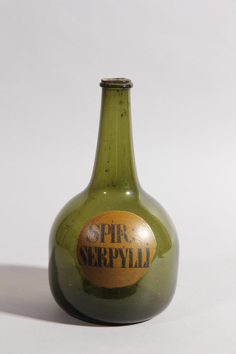 Flaska av grönt glas, rund med flat botten och lång hals.