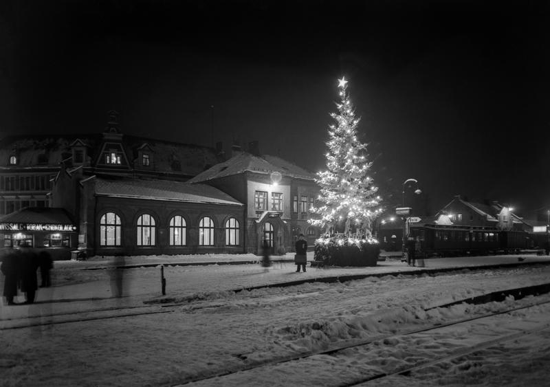 Svart-hvitt foto av julegran med mye lys som sto på perrongen på Hamar stasjon.