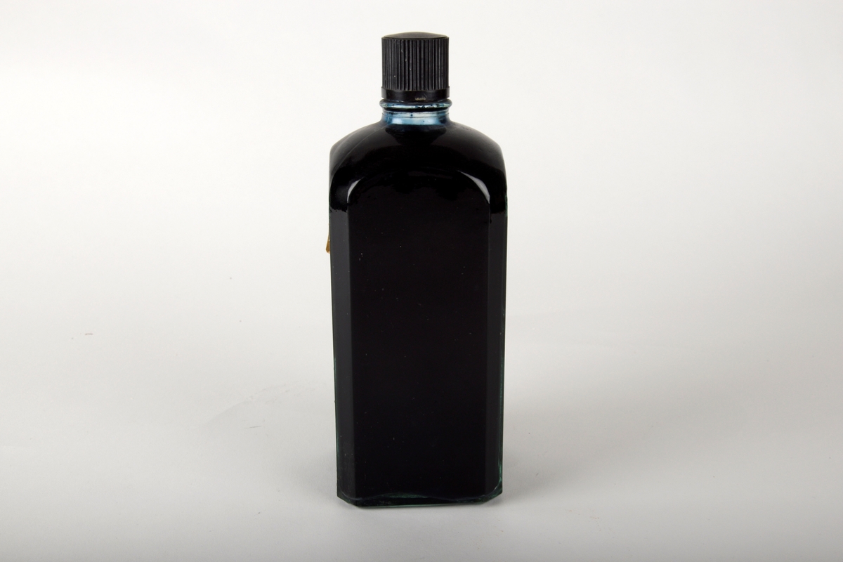 Glassflaske fylt med svart skriveblekk. Flasken har kork av plast med indenterte linjer. Hvit etikett med blå tekst og ramme på fremsiden.