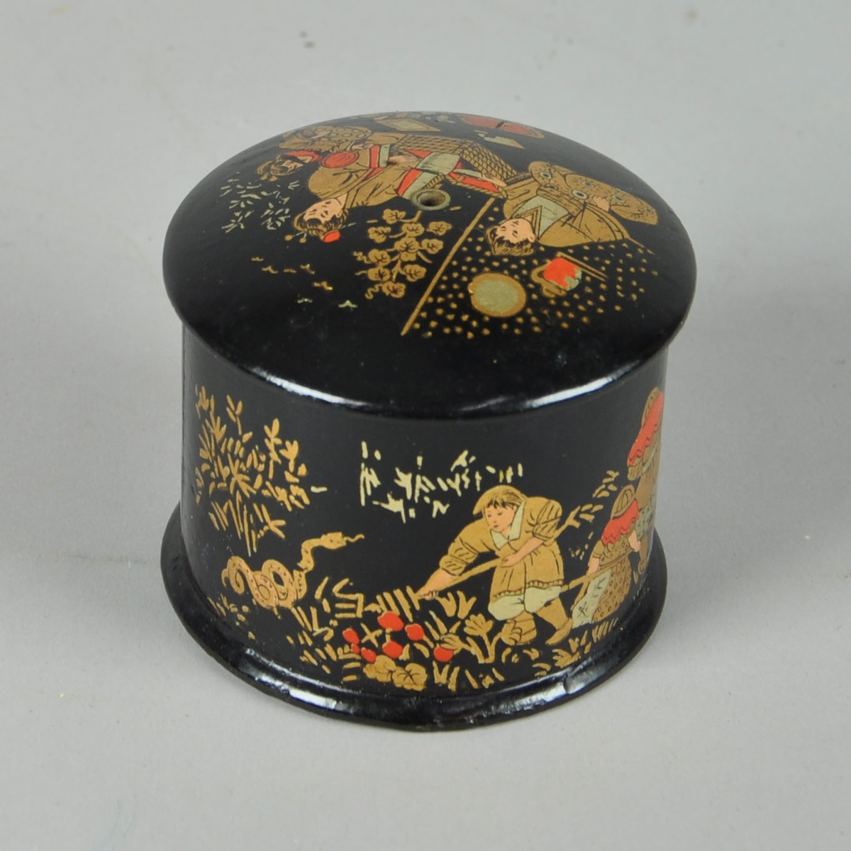 Sort nøstekopp med kinesisk-inspirert motiv. Motivet er i gull, sølv, sort og rødt. Det er både motiv på lokket og selve koppen. Nøstekoppen er sort innvendig.