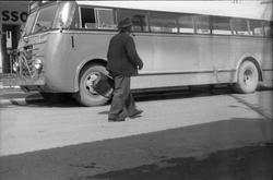 En buss og en uidentifisert fotgjenger foran Esso bensinstas