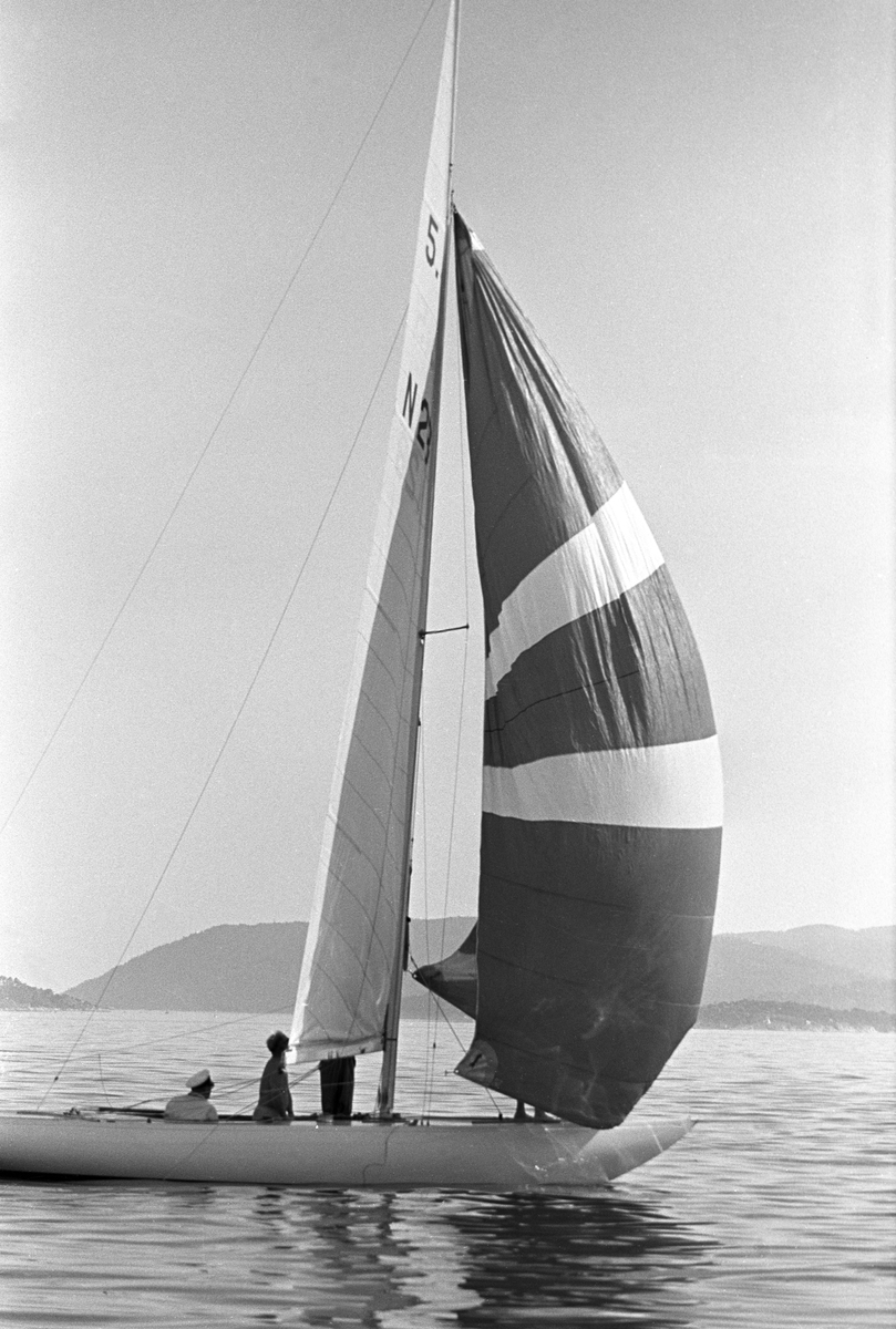 Kong Olav seiler med båten"Norna X". Kong Olav sitter i båten.