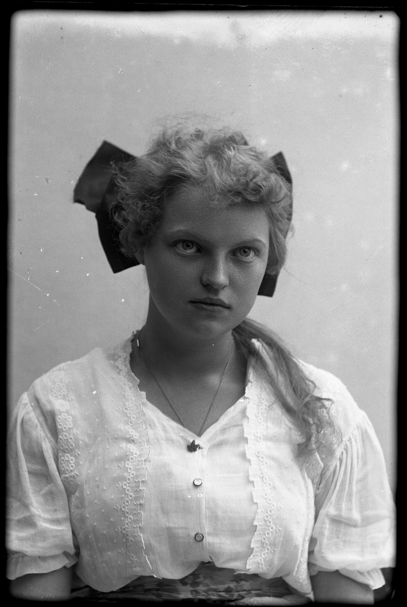 Porträtt av Greta Bengtsson i vit klänning och med mörk rosett i håret.