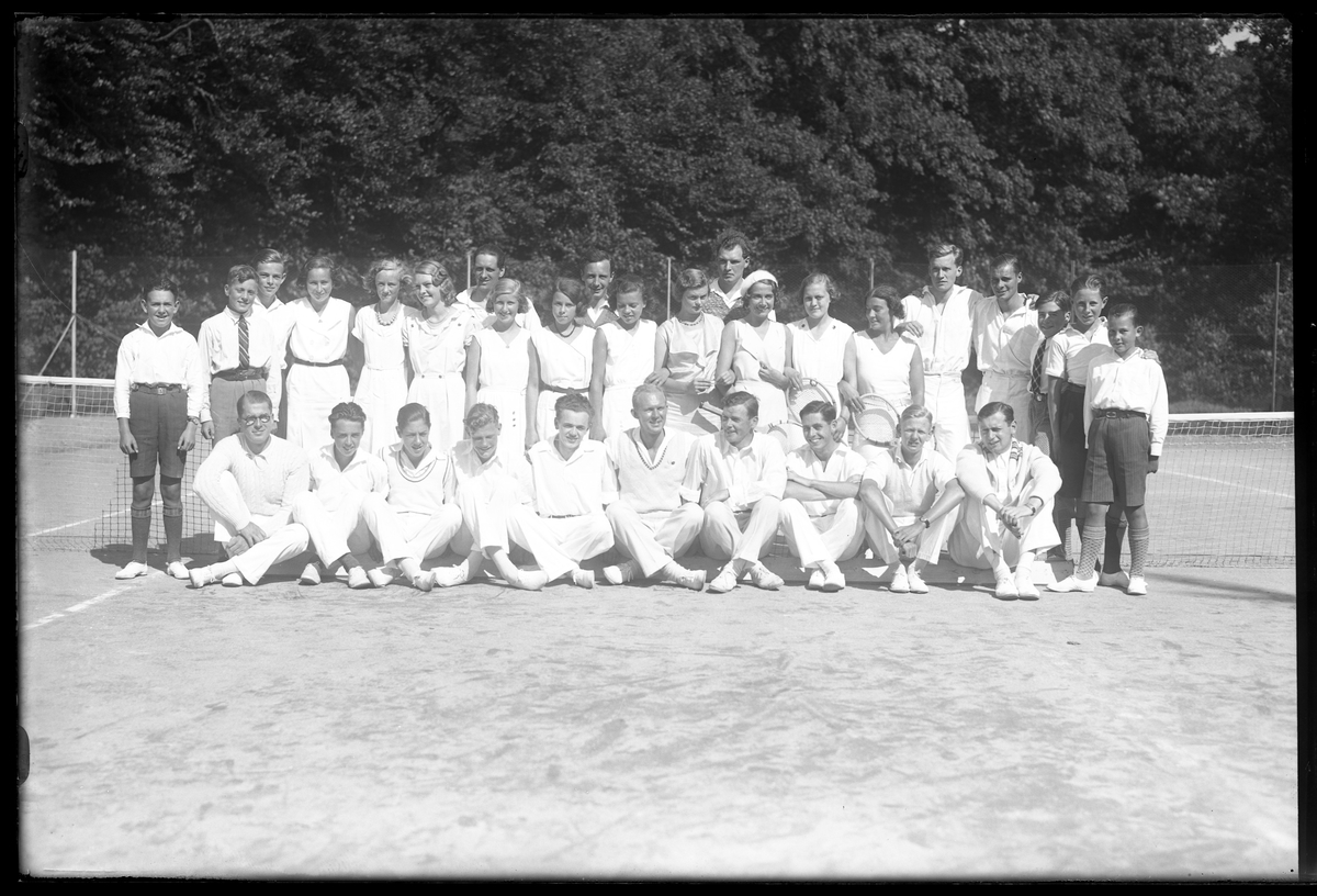 Gruppbild på medlemmar från Alingsås tennisklubb uppställda på en tennisplan.