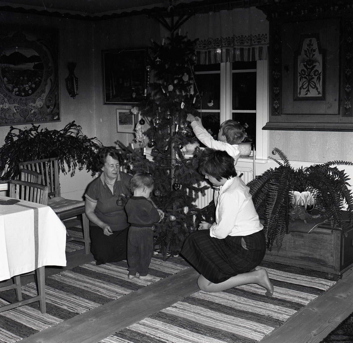Två kvinnor och två barn klär en julgran den 21 december 1985.