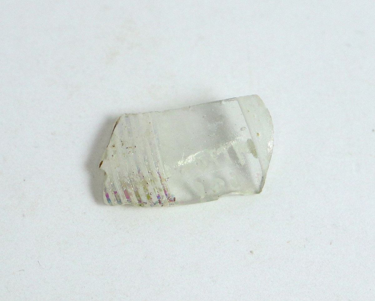 Fragment av en ventetiansk pokal av ofärgad glasmassa, med vit filigranornamnetik. Troligen en del av ett lock.