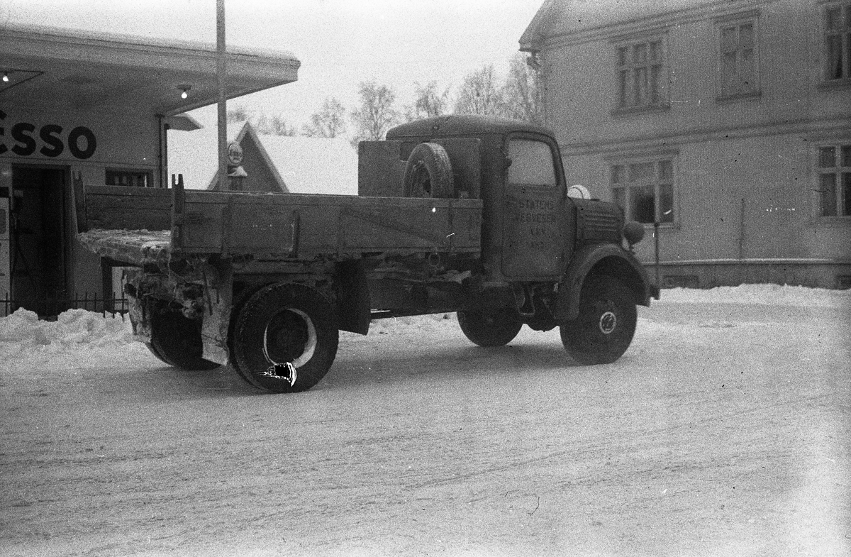 En lastebil, merket med Statens Vegvesen på døra, foran Esso bensinstasjonen på Lena mars 1954.