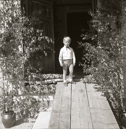 En pojke står i en dörröppning dekorerad med björklövsris, 1968.