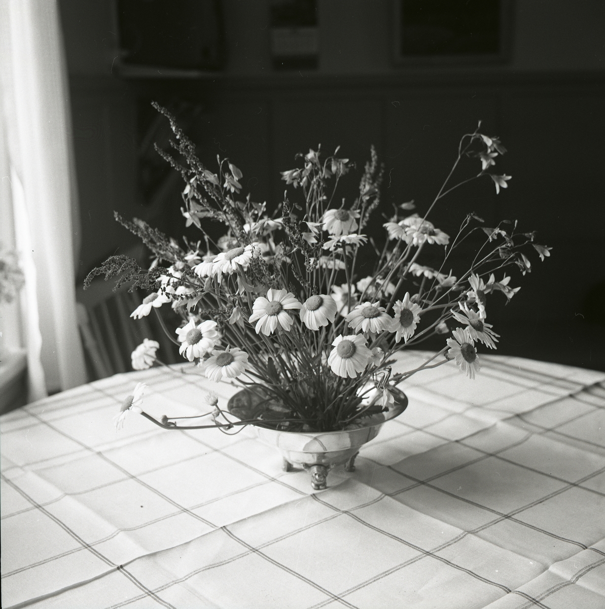Adelés midsommarbukett  i en vas står på ett bord med rutig duk, juni 1966.