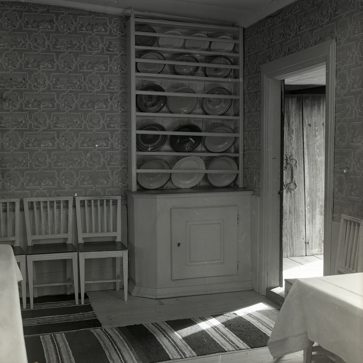 I ett rum på Karlsgården i Järvsö finns den 10 juni 1972 stolar, bord, två mattor samt en tallrikshylla.
