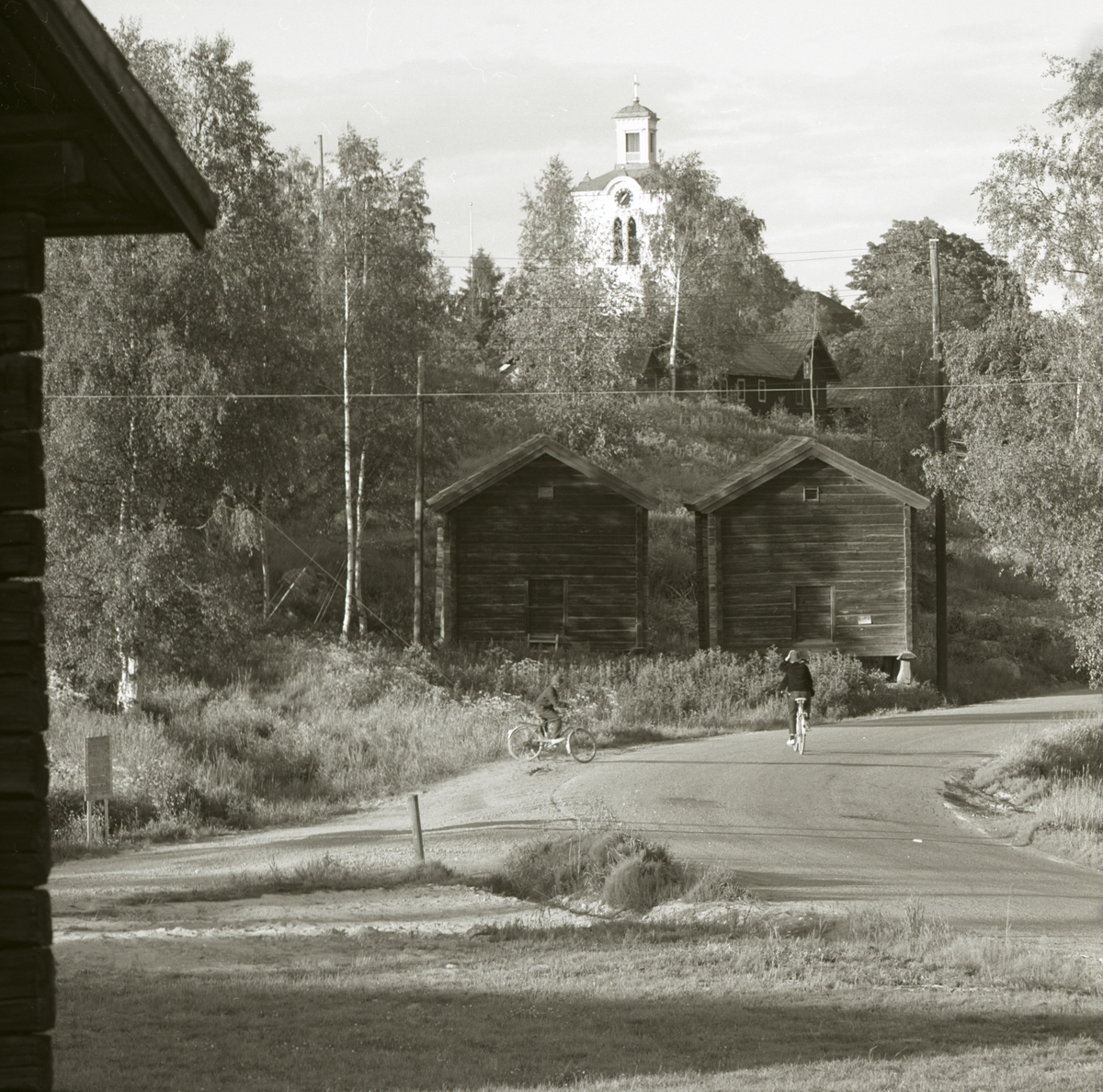 Tvillinghärbrena framför Rengsjö kyrka före rivning. Kyrkan står på en kulle bakom härbrena, 1973 i Rengsjö.