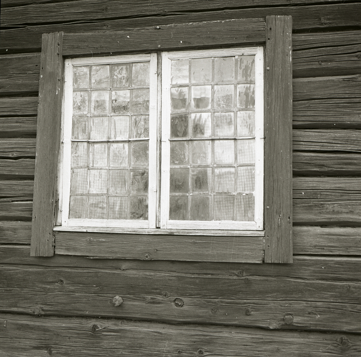 Ett fönster med blyinfattade glasrutor sitter på en av byggnaderna i Rengsjö hembygdsby, 1982.