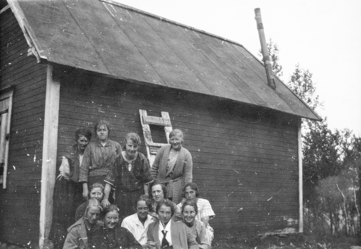 Gruppebilde av unge kvinner, tatt foran en hytte.