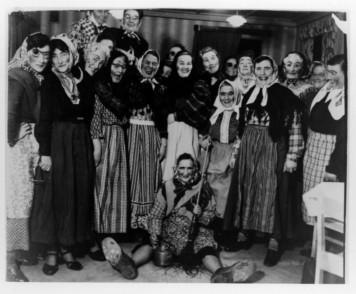 Gruppbild med omkring 20 kvinnor från Alingsås Kooperativa Kvinnogille, klädda som påskgummor under en påskfest.