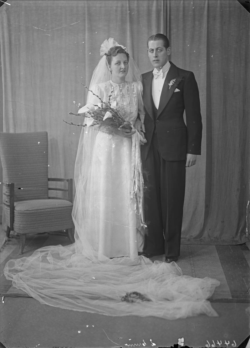 Portrett. Brudebilde. Ung kvinne i lys brudekjole med slør og ung mann i smoking med lys sløyfe. Brudepar. Bestilt av Johannes Ulveraker.