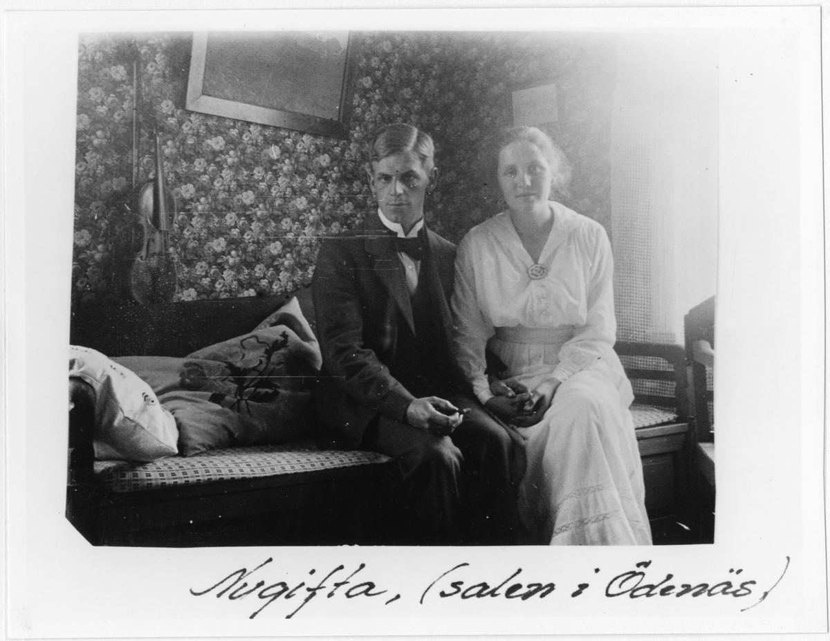 Nils och Elisabeth Henning sitter som nygifta på en soffa i hemmet på skolan i Ödenäs. Bilden är tagen i salen i Ödenäs.

Nils Henning var lärare i Ödenäs från 1915 och familjen bodde i skolan.