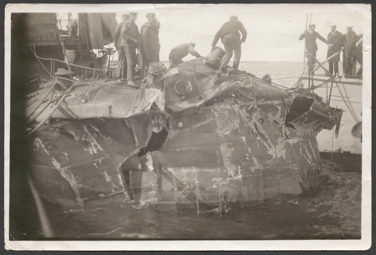 Bilden visar förskeppet av jagaren Vidar efter sammanstötningen med jagaren Wachtmeister. Skeppets förstäv är stark intryckt och sönder riven. Flera sjömän undersöker skadorna.