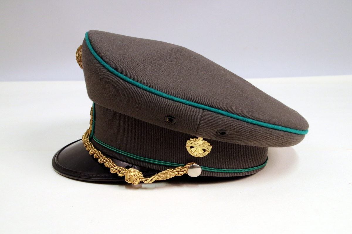 Grå uniformslue med sort lakkskjerm og detaljer i gull og grønt.
