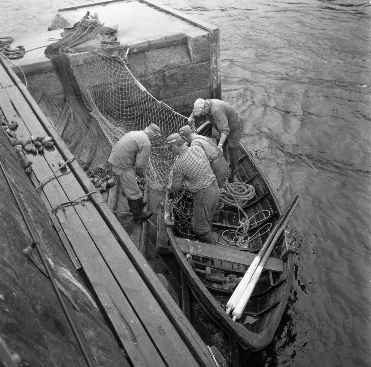 Fyra män arbetar med ett fiskenät på en båt i Ljusne 1954.