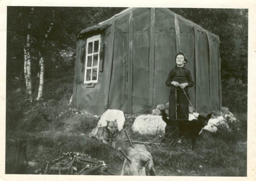 Laila Njarka utenfor hytta i Sørvassdalen, sammen med to hunder.
