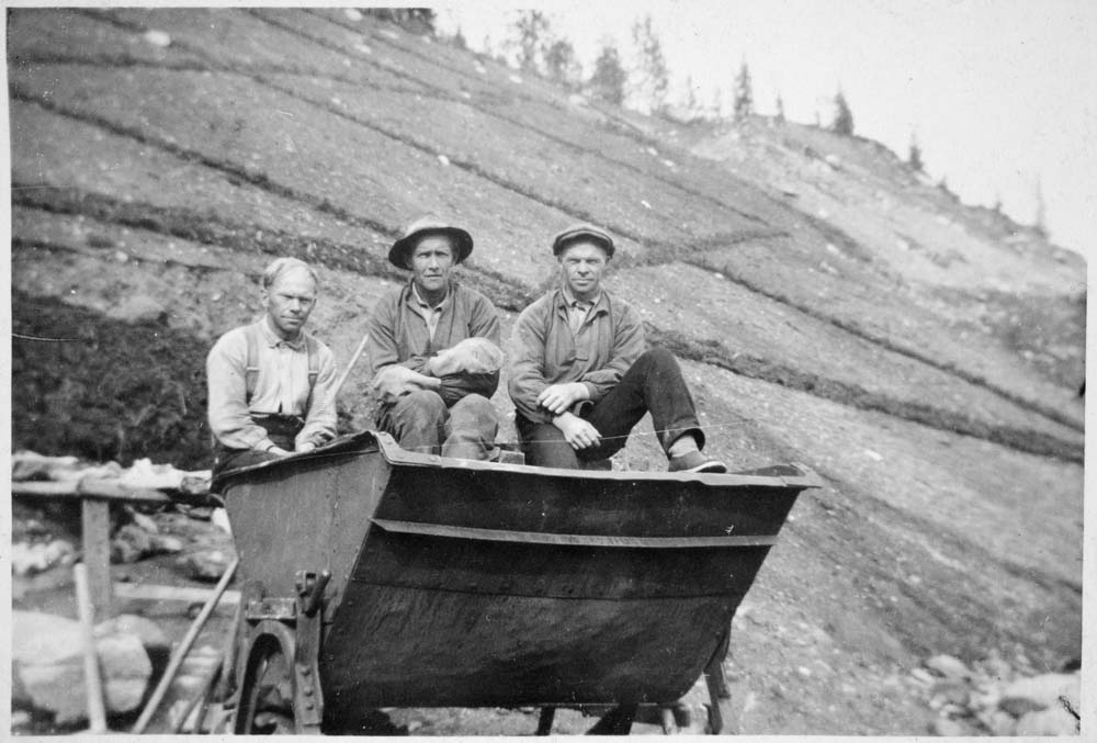 Jernbanebygging. Tre arbeidere sitter og hviler i en vagge.