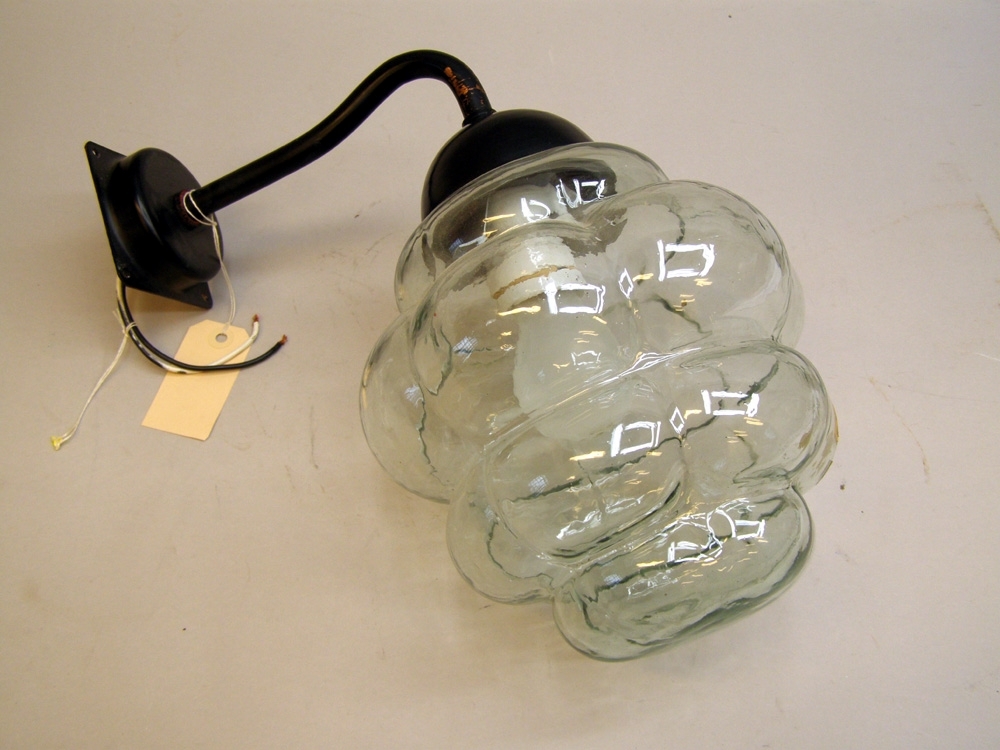 Vägglampa med svartmålad hållare och handgjort glaskupa av genomskinligt glas.