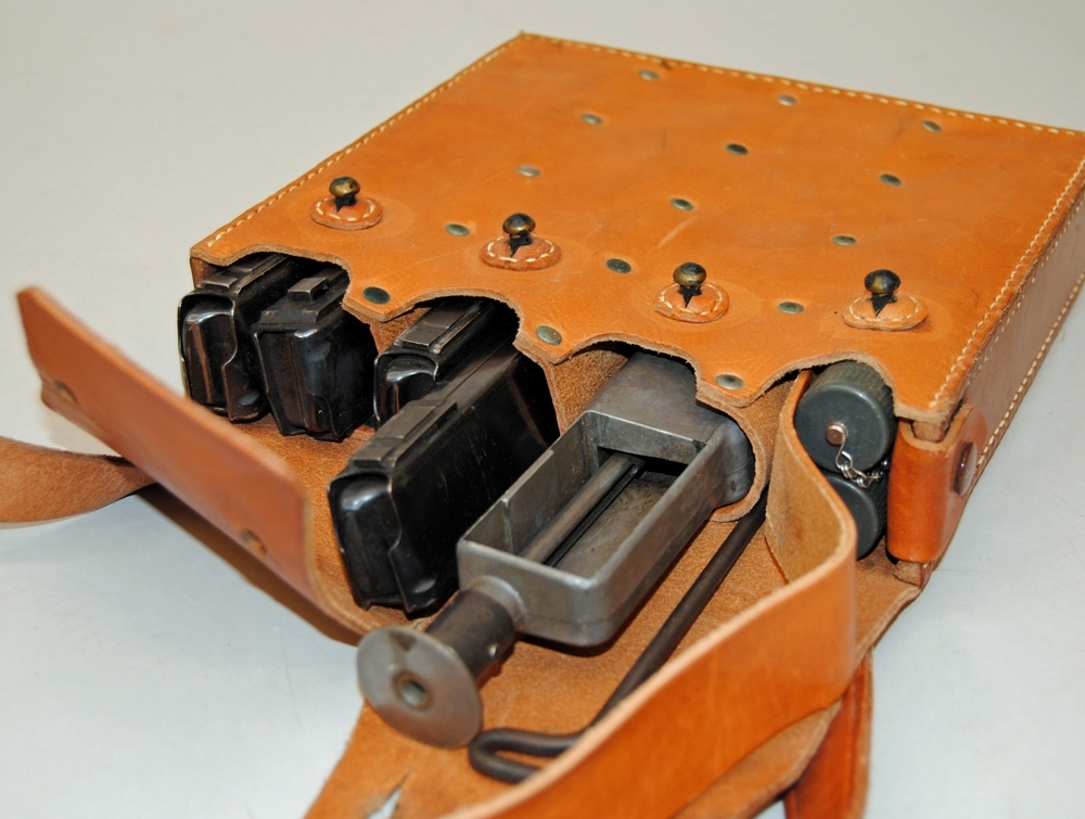 Magasinsväska till kulsprutepistol m/1937-39.
Brun läderväska för ammunition och laddare till kulsprutepistol, sydd av kraftigt läder. Väskan knäpps framtill med fyra stycken kulformade s k gevärsknappar, och fästs över axeln och bröstet med läderrem. Väskan har fyra fack, varav ett av dem med en innbygd rem för att dra ut innehållet. Väskan innehåller fyra magasin, en dubbel oljedosa för gevär, en magasinsfyllare samt en läskstång.
Jvm 21336:1 Väska
Jvm 21336:2 Magasin
Jvm 21336:3 Magasin
Jvm 21336:4 Magasin
Jvm 21336:5 Magasin
Jvm 21336:6 Läskstång
Jvm 21336:7 Magasinsfyllare
Jvm 21336:8 Oljedosa

Magasinsväskan tillhör utrustningen för en furir vid SJ:s Driftvärn.

Historik: Efter att SJ:s Driftvärn lades ner 2005 behölls en del föremål från verksamheten i ett litet 'museum' eller traditionsrum som det kallades, på den f d kursgården i Dala-Storsund i Dalarna. Kursgården var en av 12 sådana runt om i landet som från början ägdes av Statens Järnvägar. Gårdarna användes för att Driftvärnspersonalen skulle lära sig skytte, militär stridsteknik mm. Vid bolagiseringen av SJ överfördes gården till Banverket, som senare blev till Trafikverket.
Då Trafikverket i sin tur beslöt att bygga om och modernisera anläggningen 2013 revs det s k traditionsrummet och föremålen lades i förvar till Sveriges Järnvägsmuseum hämtade dem oktober 2014. Gården i Dala-Storsund anlades 1954 och var också den sista som användes.

Modell/Fabrikat/typ: m/39