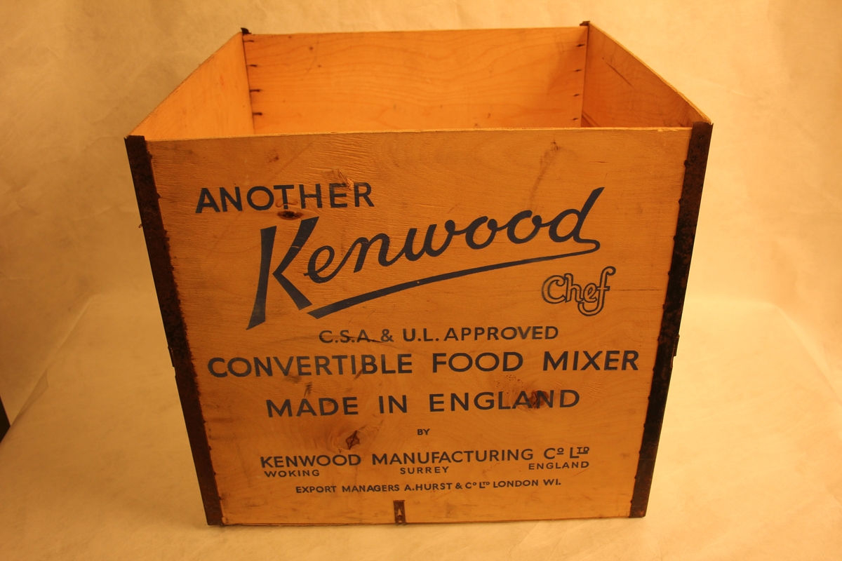 Kubisk kasse av kryssfinér med jernbeslag i hjørna. Orginalembalasje til Kenwood Chef kjøkkenmaskin.