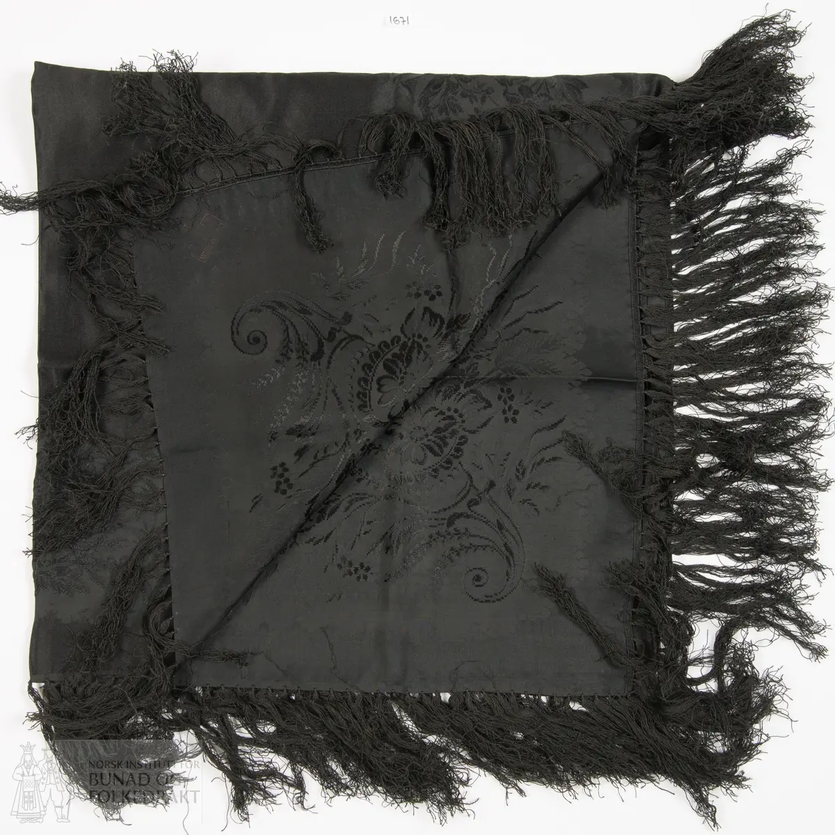 Svart mønstervove silketørkle med påknytte silkefrynser. Tørkledet er vove med satengbotn. Stiv og fast kvalitet.