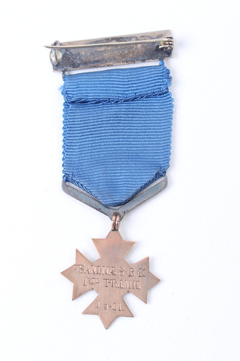 Stjerneformet medalje med blått medaljebånd og agraff.